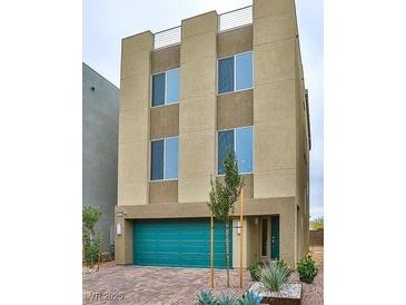 Modern three-story home featuring a bold teal garage door, stucco facade, and well-manicured desert landscaping at 8055 Haywood Estate Ave, Las Vegas, NV 89113