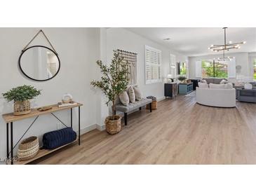 Bright living room features wood floors, light gray sofas, neutral decor, and large windows with plantation shutters at 10368 Mystic Pine Rd, Las Vegas, NV 89135