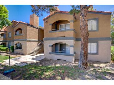 Two-story condo with a stucco exterior, gray accents, and a staircase leading to the upper level at 220 Mission Newport Ln # 105, Las Vegas, NV 89107