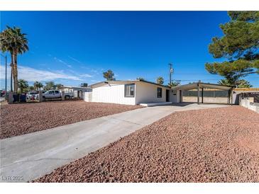 Single-story home featuring a gravel front yard, long driveway, and covered carport against a clear, blue sky at 2878 El Cajon St, Las Vegas, NV 89169