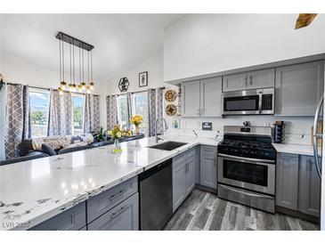 Modern kitchen featuring gray cabinetry, stainless steel appliances, and a breakfast bar overlooking the living area at 7241 Indian Creek Ln # 203, Las Vegas, NV 89149