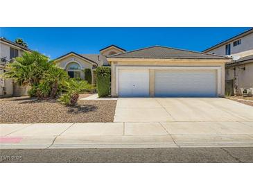 Charming single-story home featuring a spacious driveway leading to a two-car garage and desert landscaping at 5413 Flora Spray St, Las Vegas, NV 89130