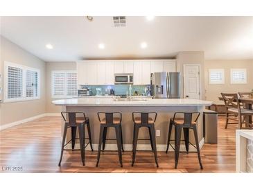 Kitchen island with barstool seating, stainless appliances, granite countertops, and wood floors at 5733 Dazzling Sparks St, North Las Vegas, NV 89031