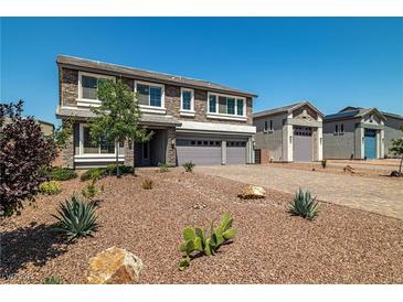 Beautiful two-story home featuring a stone facade, three-car garage, and desert landscaping at 8753 Mann St, Las Vegas, NV 89139