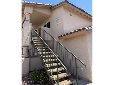 Charming condo exterior featuring stairs leading up to the entrance with neutral stucco and dark railings at 1320 Driscoll Dr # 201, Las Vegas, NV 89128