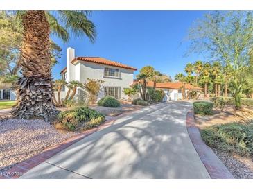 Stunning white home with a red tile roof, desert landscaping, and a long private drive leading up to the house at 2868 Vista Del Sol Ave, Las Vegas, NV 89120