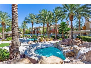 Community pool and spa area with palm trees, waterfall features, and lounge chairs at 10640 Amber Ridge Dr # 101, Las Vegas, NV 89144