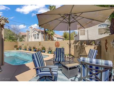 Inviting backyard pool area with comfortable seating and shaded umbrella for relaxation at 1604 Imperial Cup Dr, Las Vegas, NV 89117