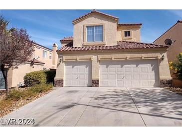 Two-story home featuring a two-car garage, tan stucco exterior, and a well-maintained driveway in a suburban neighborhood at 256 Camino Viejo St, Henderson, NV 89012