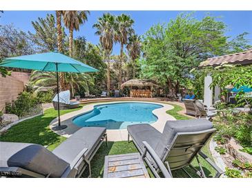 Backyard pool featuring lush tropical landscaping, a swim-up bar, lounge chairs, and a beautiful patio area at 2608 Prospector Mine Ave, North Las Vegas, NV 89031