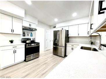 Modern kitchen featuring white cabinets, stainless steel appliances, and light wood flooring at 4324 El Conlon Ave, Las Vegas, NV 89102