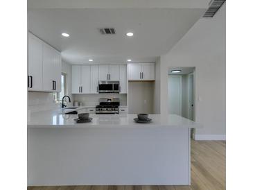 Bright kitchen features white cabinetry, stainless steel appliances, and a large island with a white countertop at 5742 Forsythe Dr, Las Vegas, NV 89142