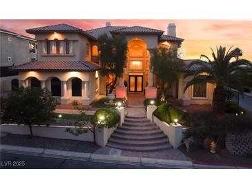 Elegant stucco home with an arched entryway, steps to the front door, and professionally landscaped front yard at sunset at 761 Romano Ln, Henderson, NV 89012