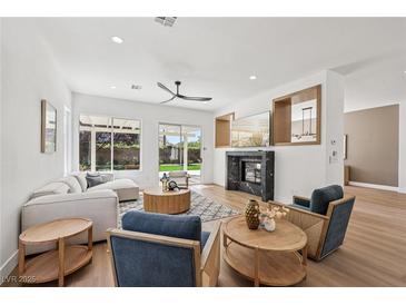 Bright, open living room with modern fireplace, recessed lighting, and sliding doors to the backyard at 2297 Aria Dr, Henderson, NV 89052