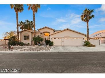 Inviting single-story home with a neutral-colored exterior, palm trees, and a spacious three-car garage at 303 Hidden Highlands Dr, Las Vegas, NV 89110