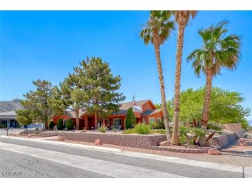 Inviting home with desert landscaping, palm trees, and unique red-colored walls at 4045 N Chieftain St, Las Vegas, NV 89129
