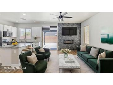 Cozy living room featuring modern fireplace, stylish seating, and an open-concept design to the kitchen at 6525 Raven Hall St, North Las Vegas, NV 89084