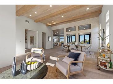 Open-concept living room with wood-beamed ceilings, white brick accent wall, and seamless flow to dining and kitchen areas at 2508 Faiss Dr, Las Vegas, NV 89134
