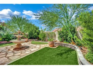 Beautiful backyard with a stone fountain, artificial grass, mature trees and landscaping at 326 Caneflower Ct, North Las Vegas, NV 89031