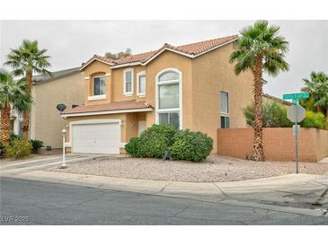 Two-story home featuring a tile roof, two-car garage, desert landscaping, and mature palm trees at 6007 Turtle River Ave, Las Vegas, NV 89156