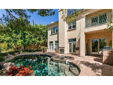 Beautiful backyard pool and spa with stone patio and stucco house at 9001 Opus Dr, Las Vegas, NV 89117