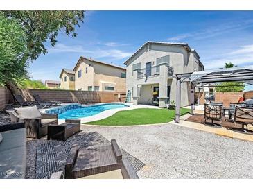 Inviting backyard featuring a pool, artificial grass, and comfortable seating areas, perfect for relaxation and entertaining at 3591 Gloucester Gate St, Las Vegas, NV 89122
