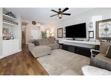 Inviting living room with a plush rug, modern ceiling fan, and large screen television at 5131 Moose Falls Dr, Las Vegas, NV 89141