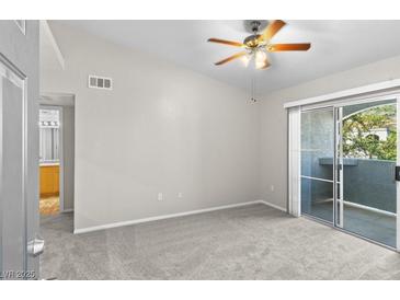 Bright bedroom featuring neutral carpet, sliding glass door, and ceiling fan with light fixture at 6955 N Durango Dr # 2054, Las Vegas, NV 89149