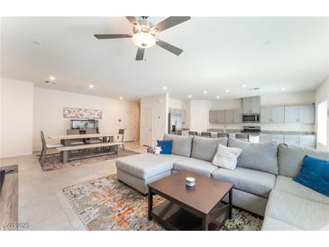 Open-concept living room with plush sectional sofa, adjacent kitchen and dining areas bathed in natural light at 7211 Alabaster Peak St, Las Vegas, NV 89166