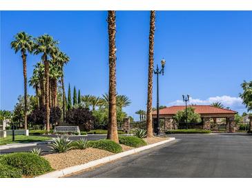 Gated community entrance featuring lush landscaping and mature palm trees under a clear blue sky at 7889 Rancho Mirage Dr, Las Vegas, NV 89113