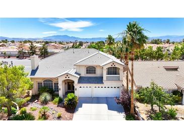 Charming two-story home featuring a well-manicured lawn, palm trees, a balcony, and a three-car garage at 9155 Harvest Homes St, Las Vegas, NV 89123
