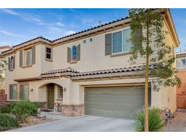 Two-story home with a tile roof, a two-car garage, and mature landscaping in front at 9715 Aleutian St, Las Vegas, NV 89178