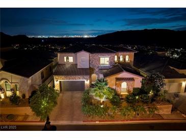 Stunning two-story home with lush landscaping and a view of the Las Vegas skyline at night at 29 Costa Tropical Dr, Henderson, NV 89011