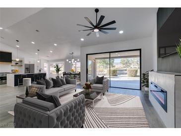 Open-concept living room featuring modern furnishings, a fireplace, and sliding glass doors to the outdoor space at 2905 Legend Dr, Las Vegas, NV 89134