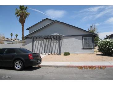 View of a gray, two-story home with a trellis over the front door and desert landscaping at 4015 Edgeford Pl, Las Vegas, NV 89102
