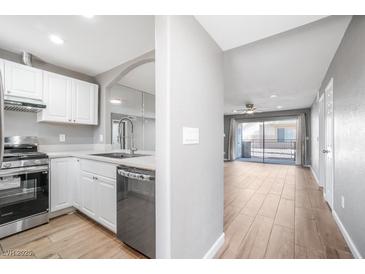 Bright kitchen featuring white cabinets, stainless steel appliances, and an open layout to the living area at 5000 Red Rock St # 120, Las Vegas, NV 89118