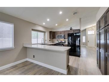 Open kitchen boasts stainless appliances, brown cabinetry, recessed lighting, and a breakfast bar at 87 Ginger Lily Ter, Henderson, NV 89074