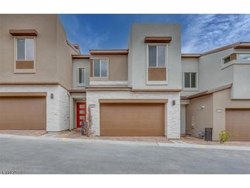 Stylish townhome showcasing a two-car garage, modern architecture, and a red front door at 11904 Glide Reflection Ave, Las Vegas, NV 89138
