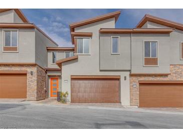 Modern townhomes with stone accents, brown garages, and eye-catching orange front doors at 11922 Glide Reflection Ave, Las Vegas, NV 89138