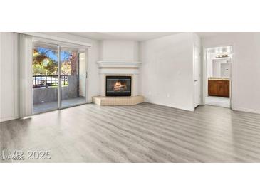 Bright living room with a cozy fireplace, modern flooring and a sliding glass door to a balcony at 2606 S Durango Dr # 276, Las Vegas, NV 89117