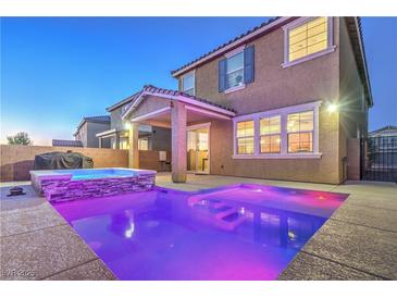 Backyard view of a stunning pool and hot tub illuminated at twilight and covered patio of home at 2787 Donatello Manor Pl, Henderson, NV 89044
