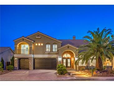 Elegant two-story home featuring a three-car garage, arched entry, stone accents, and lush palm tree in landscaped yard at 4045 Abernethy Forest Pl, Las Vegas, NV 89141