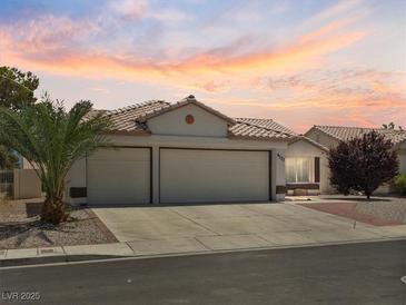 Charming single-story home with a three car garage and tile roof at sunset at 4323 Pageantry Falls Dr, North Las Vegas, NV 89031