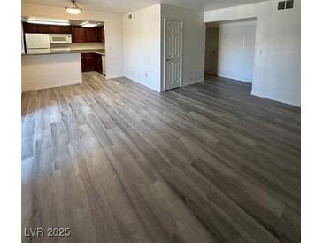 Bright living room featuring modern, wood-look flooring and a view into the kitchen area at 5251 Indian River Dr # 271, Las Vegas, NV 89103