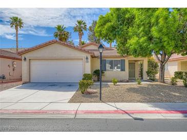 Charming single-story home featuring a two-car garage, desert landscaping, and mature shade trees at 7547 Rolling River Dr, Las Vegas, NV 89131