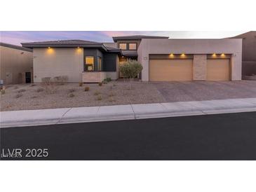 Contemporary home featuring a three-car garage and desert landscaping in the front yard at 11015 Sanctuary Cove Ct, Las Vegas, NV 89135