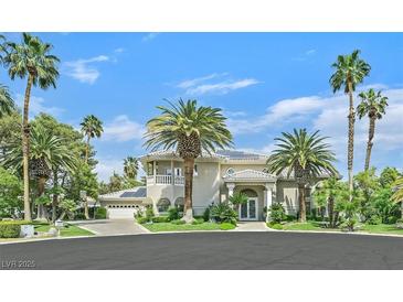 Stately stucco home featuring lush landscaping, a circular driveway, and ample palm trees at 3372 Westwind Rd, Las Vegas, NV 89146