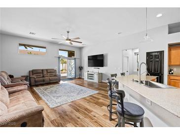 Inviting living room features an open floor plan, wood floors, neutral tones, and sliding door access to the outdoors at 4212 Helens Pouroff Ave, North Las Vegas, NV 89085