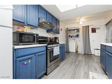 Cozy kitchen featuring blue cabinetry, modern appliances, and a skylight for natural lighting at 4232 Park Ct, Las Vegas, NV 89110