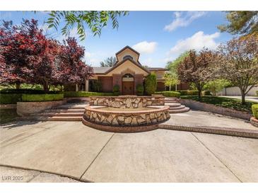 Stately home showcasing a tiered fountain, lush landscaping, and a brick facade at 112 Quail Run Rd, Henderson, NV 89014
